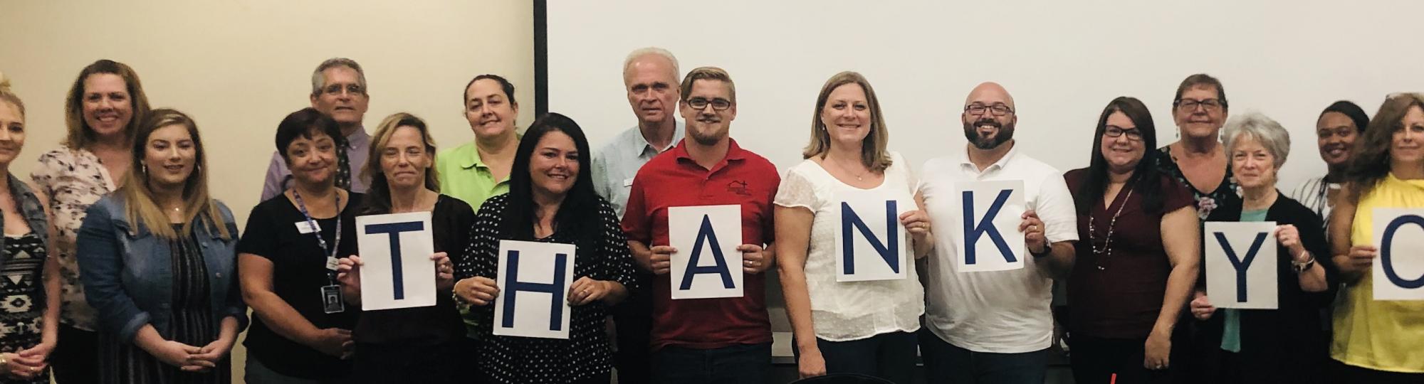 a group of representatives from UW partner agencies standing in a line, holding a sign that says Thank You